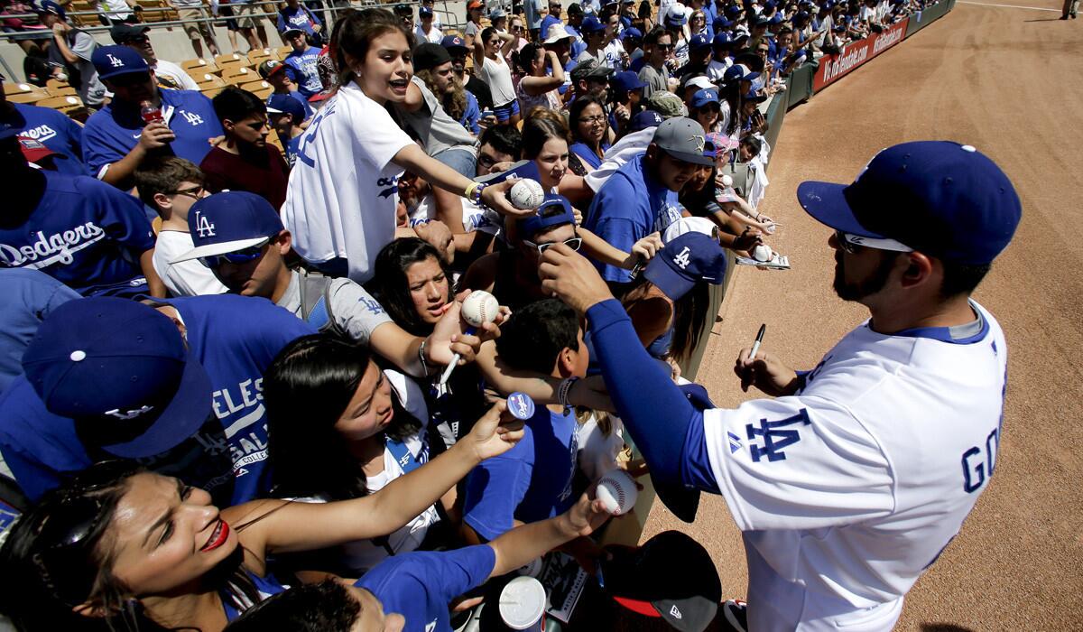 Dodgers first baseman Adrian Gonzalez signs autographs before a spring training baseball exhibition game in Glendale, Ariz.