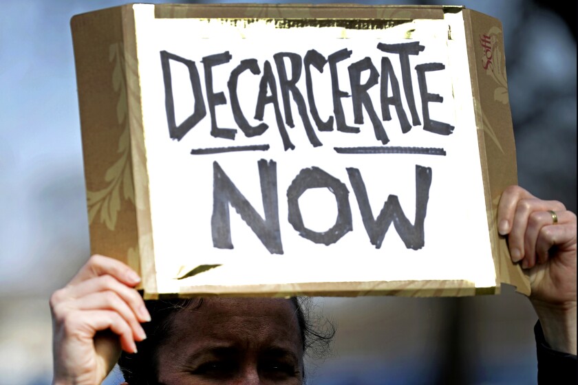 A woman holds a sign during a protest outside the Cook County Jail in Chicago, Friday, April 10, 2020, calling for the release of prisoners from the jail. A federal judge ordered Cook County Jail to take prompt action to stop the spread of the coronavirus, including by making sure that the more than 4,000 detainees have access to adequate soap and sanitizer. (AP Photo/Nam Y. Huh)