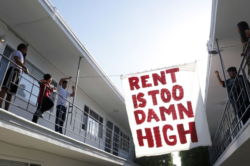 LONG BEACH, CA- June 15, 2018: Organizers with Housing Long Beach, a local advocacy group pushing for rent control and eviction protections, hangs up a sign in the courtyard of the apartment complex on Cedar Ave., during a movie night they helped put on with tenants. (Katie Falkenberg / Los Angeles Times)
