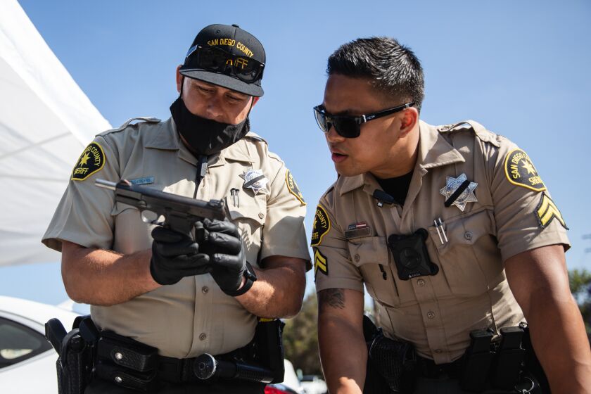 Deputy sheriffs Michael Saunders and Michael Alcarion examine a pistol that was given away during a gun buyback exchange at Encanto Southern Baptist Church on Saturday, June 5. Pistols and rifles were exchanged for $100 and $200 gift cards.