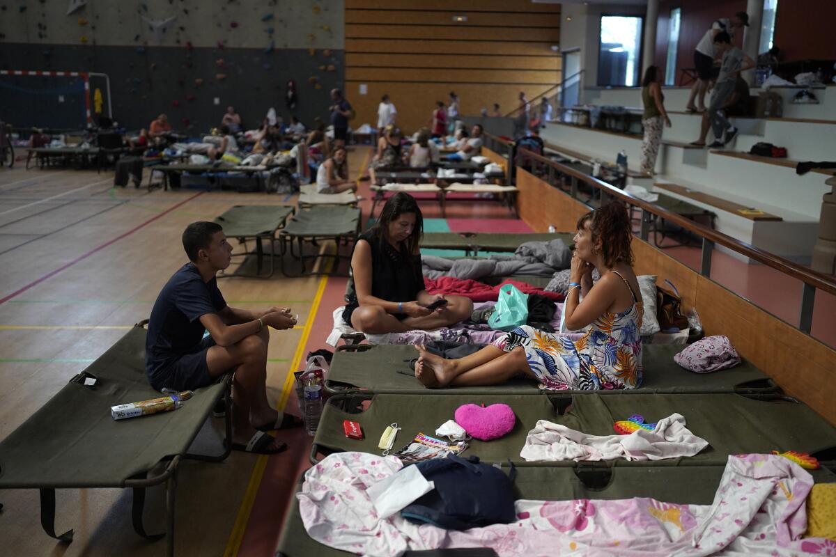 Evacuated campers rest in a gymnasium in Bormes-les-Mimosas, southern France, Wednesday, Aug. 18, 2021. Firefighters have been able to "stabilize" the blaze that raced Tuesday through forests near the French Riviera, forcing thousands of people to flee homes, campgrounds and hotels in a picturesque area beloved by residents and tourists alike.. (AP Photo/Daniel Cole)