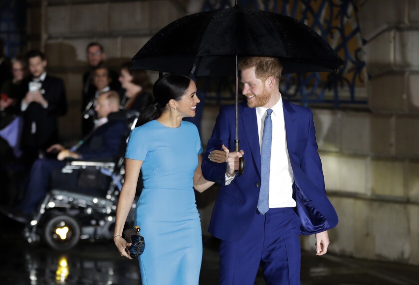 Britain's Prince Harry and Meghan walking together under an umbrella in London.
