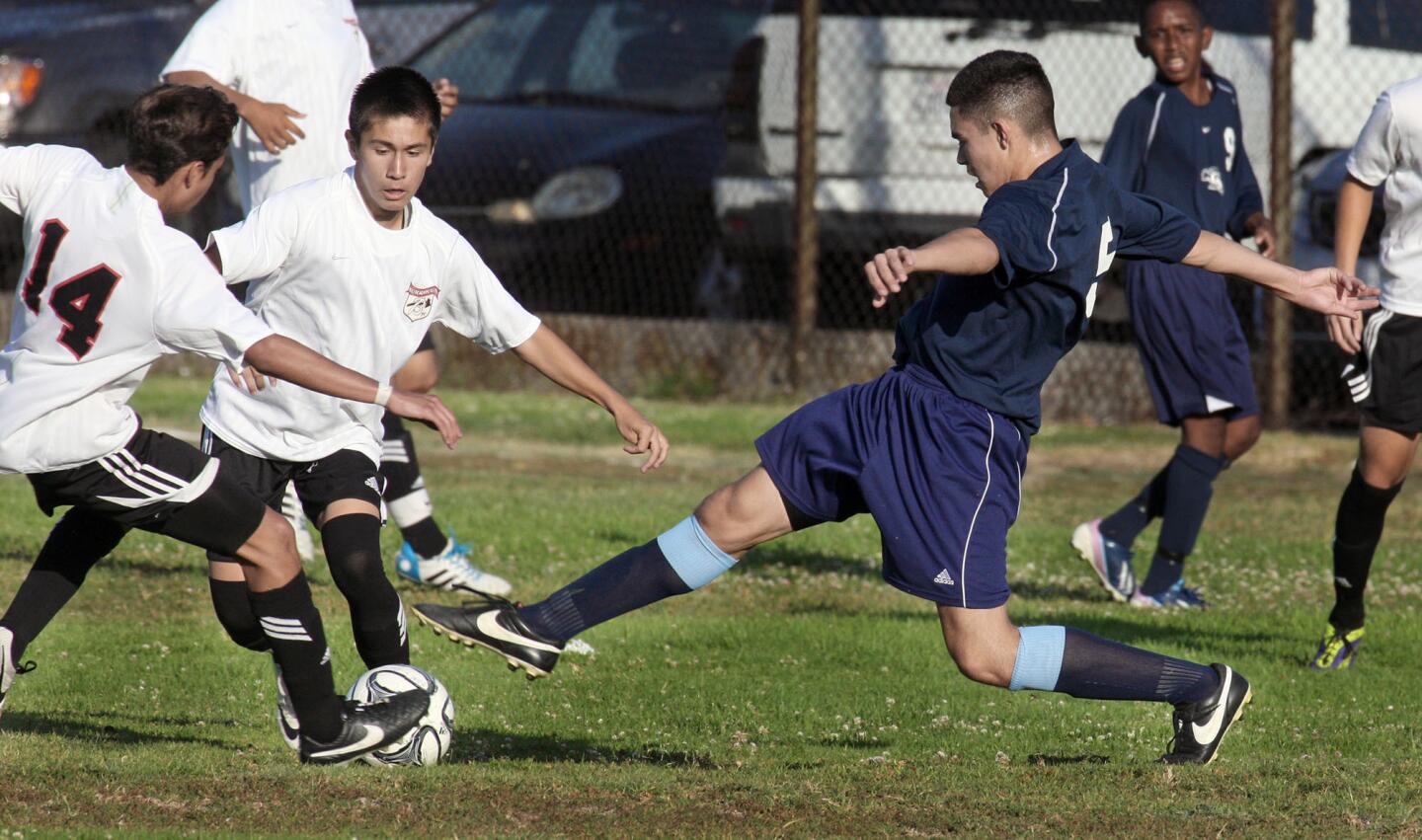 CV's Joshua Moran kicks the ball between two Burroughs defenders during a match on Wednesday, June 18, 2014.