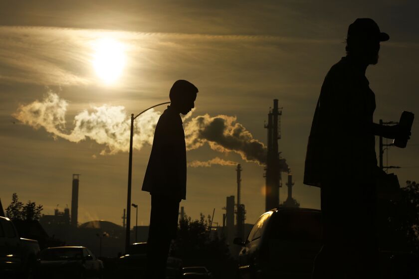 A boy and his grandfather stand near the Phillips 66 refinery in Wilmington.