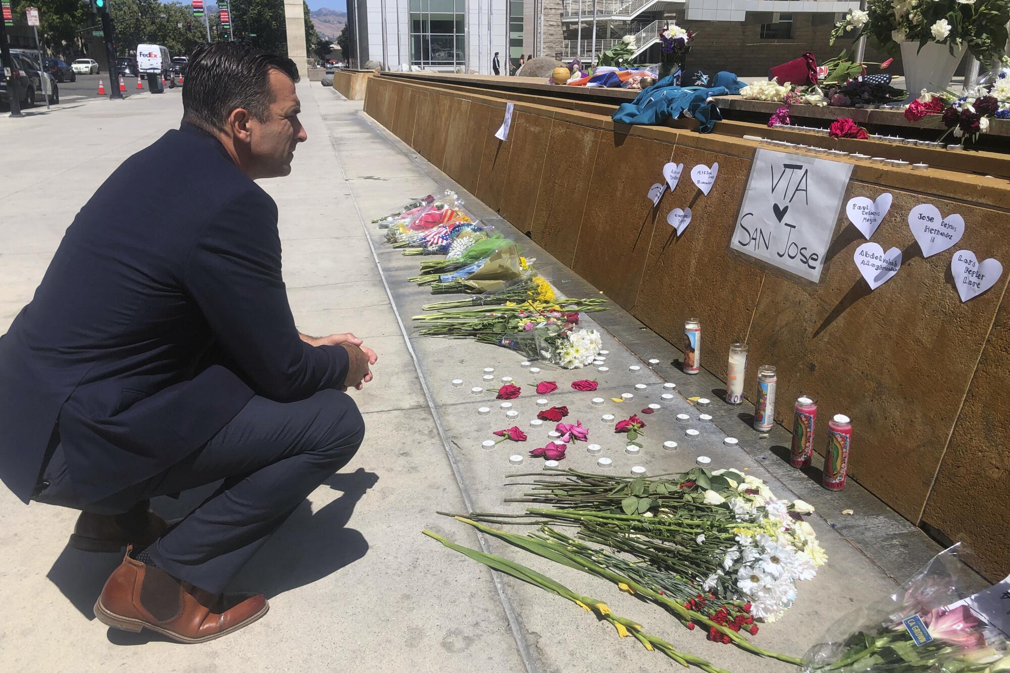 A person crouches down in front flowers on the ground.