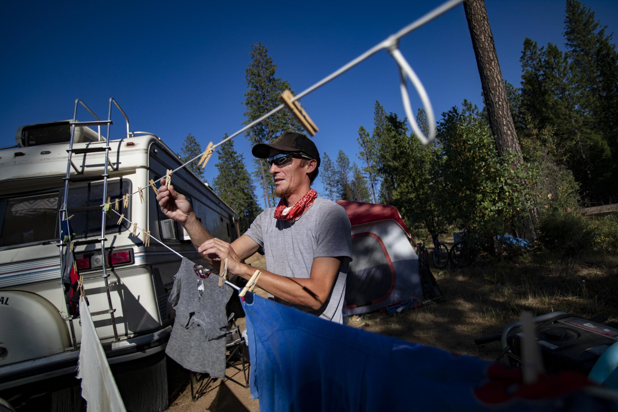 Lucas Anderson pins clothes to a line next to a trailer.