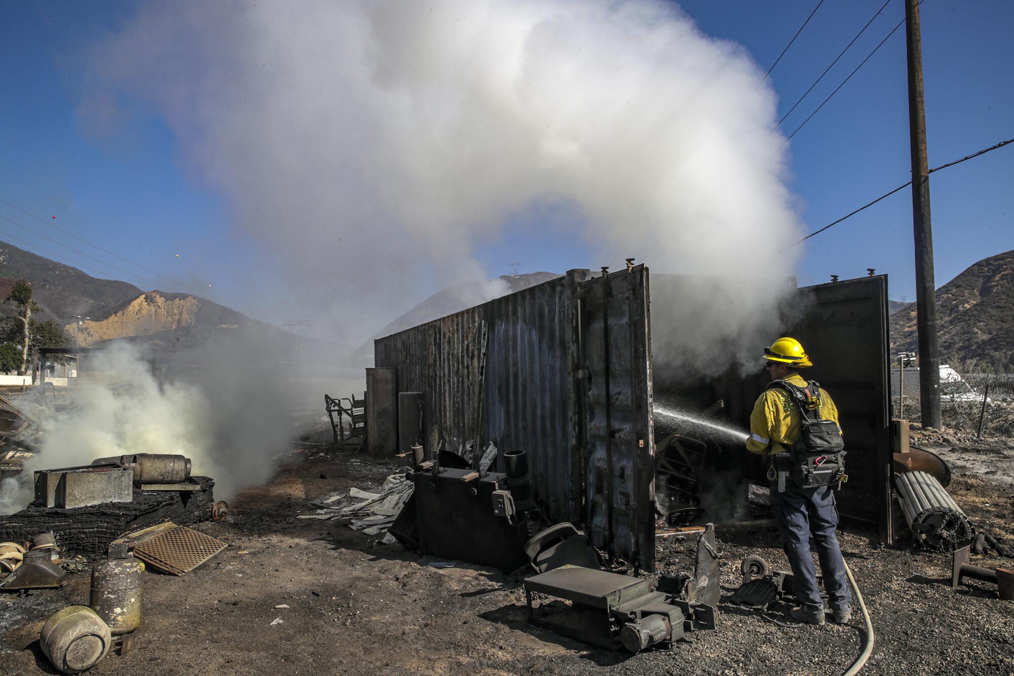 San Bernardino County firefighter Mathew Safdeye sprays a cargo container left smoldering by the South fire.
