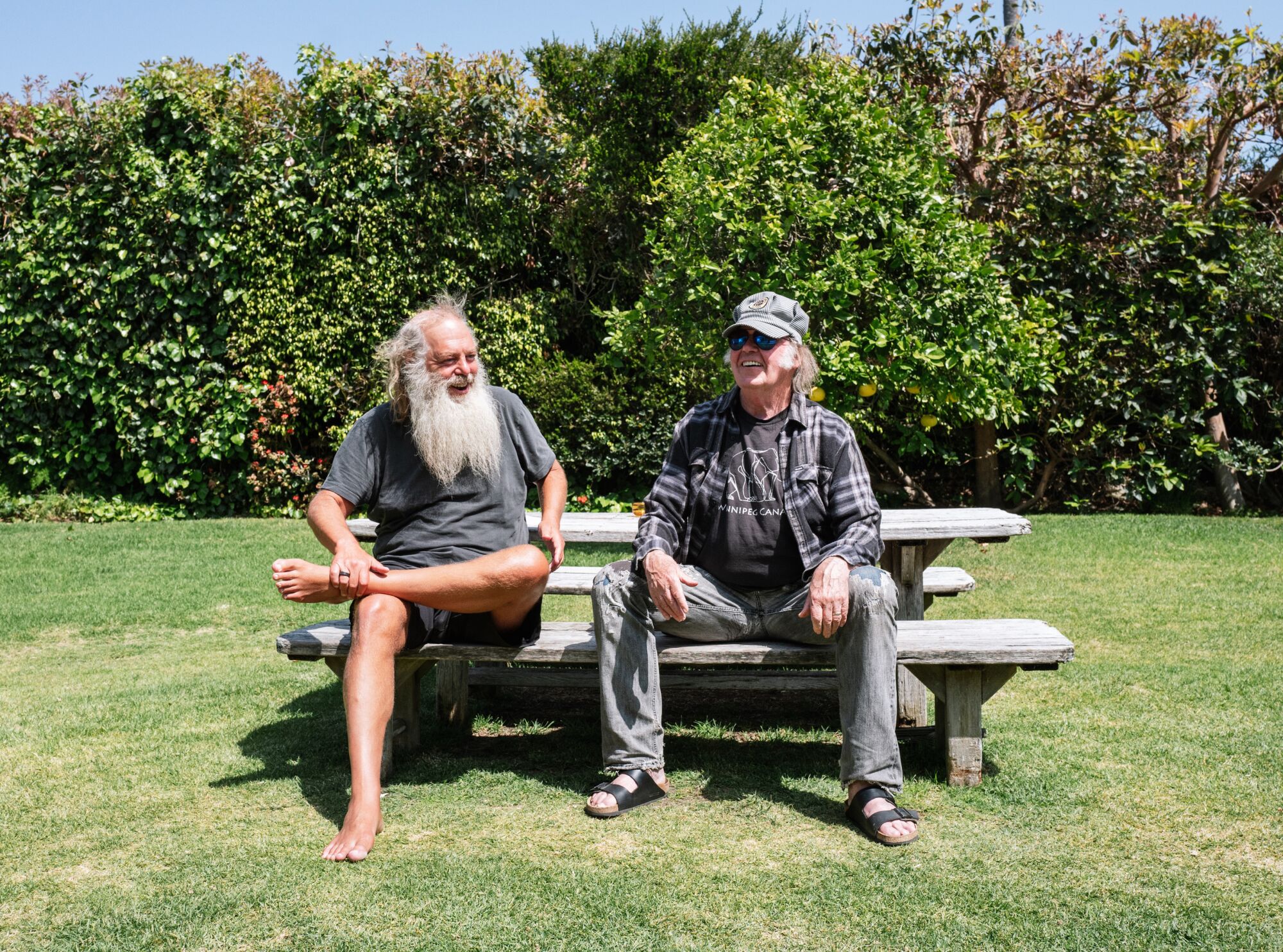 Rick Rubin and Neil Young sit at an outdoor picnic table.