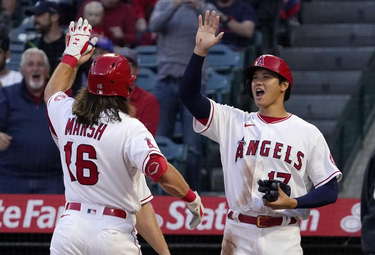 Angels' Brandon Marsh is congratulated by Shohei Ohtani and Max Stassi after hitting a three-run home run.