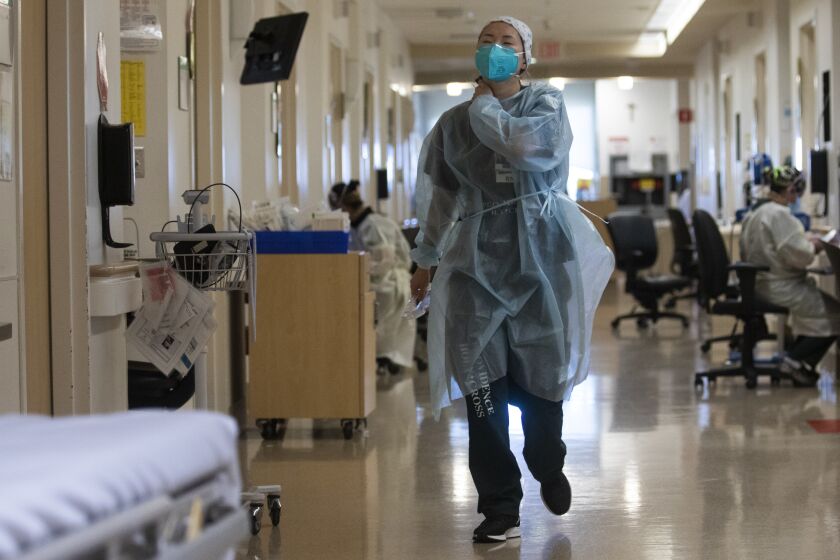 MISSION HILLS, CA - JANUARY 14: Wearing a white cap with small blue flowers her friend gave her, Registered Nurse Rebekah Park, (CQ) walks through the cover unit inside Providence Holly Cross Medical Center on Thursday, Jan. 14, 2021 in Mission Hills, CA. (Francine Orr / Los Angeles Times)