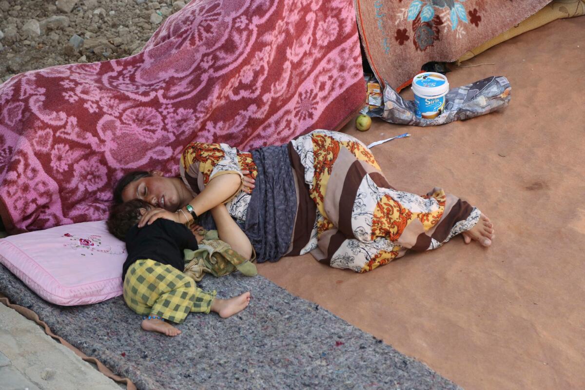 An Yazidi woman and her daughter sleep under a bridge in the northern Iraqi city of Dahuk on Aug. 14.