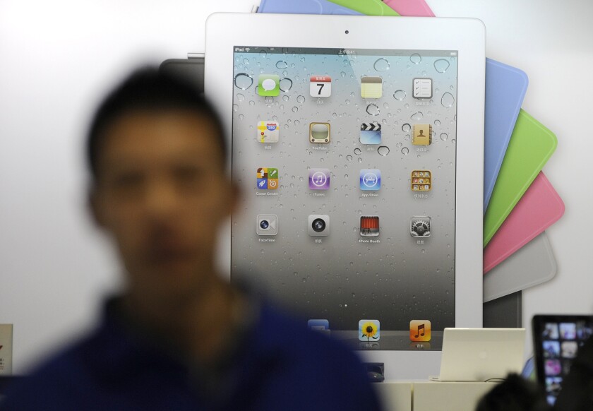 A salesman stands in front of an Apple iPad ad at an Apple store in Beijing on Wednesday.