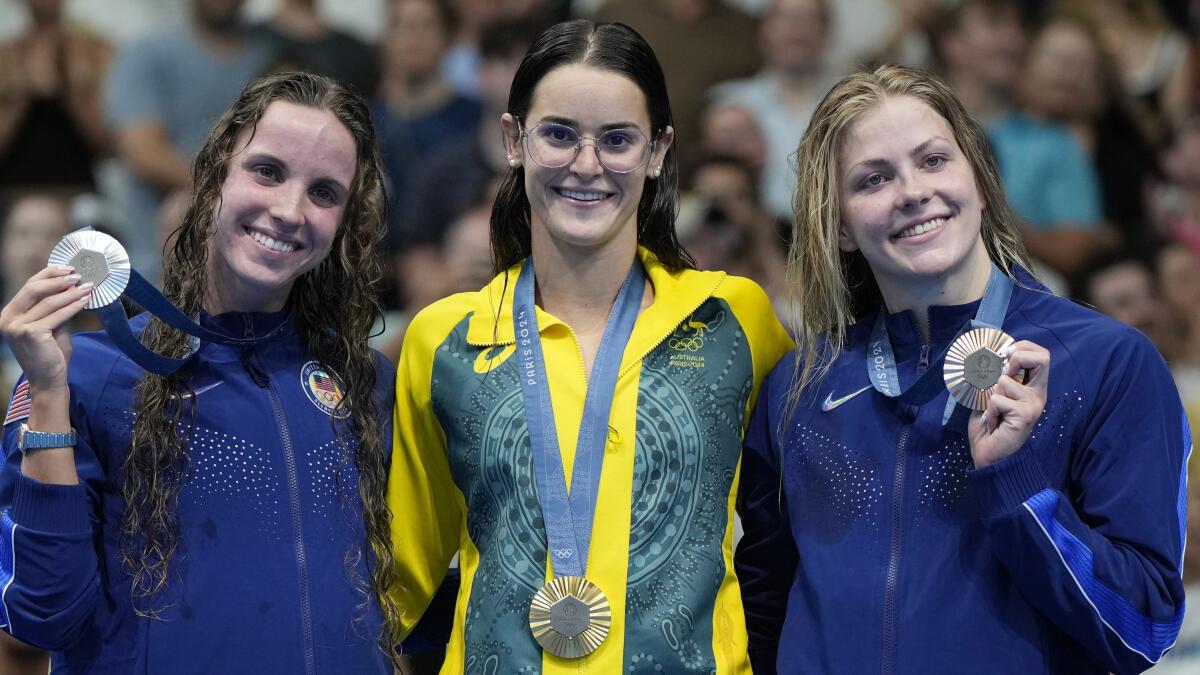 Kaylee McKeown, of Australia, stands on a podium beside Americans Regan Smith and Katherine Berkoff