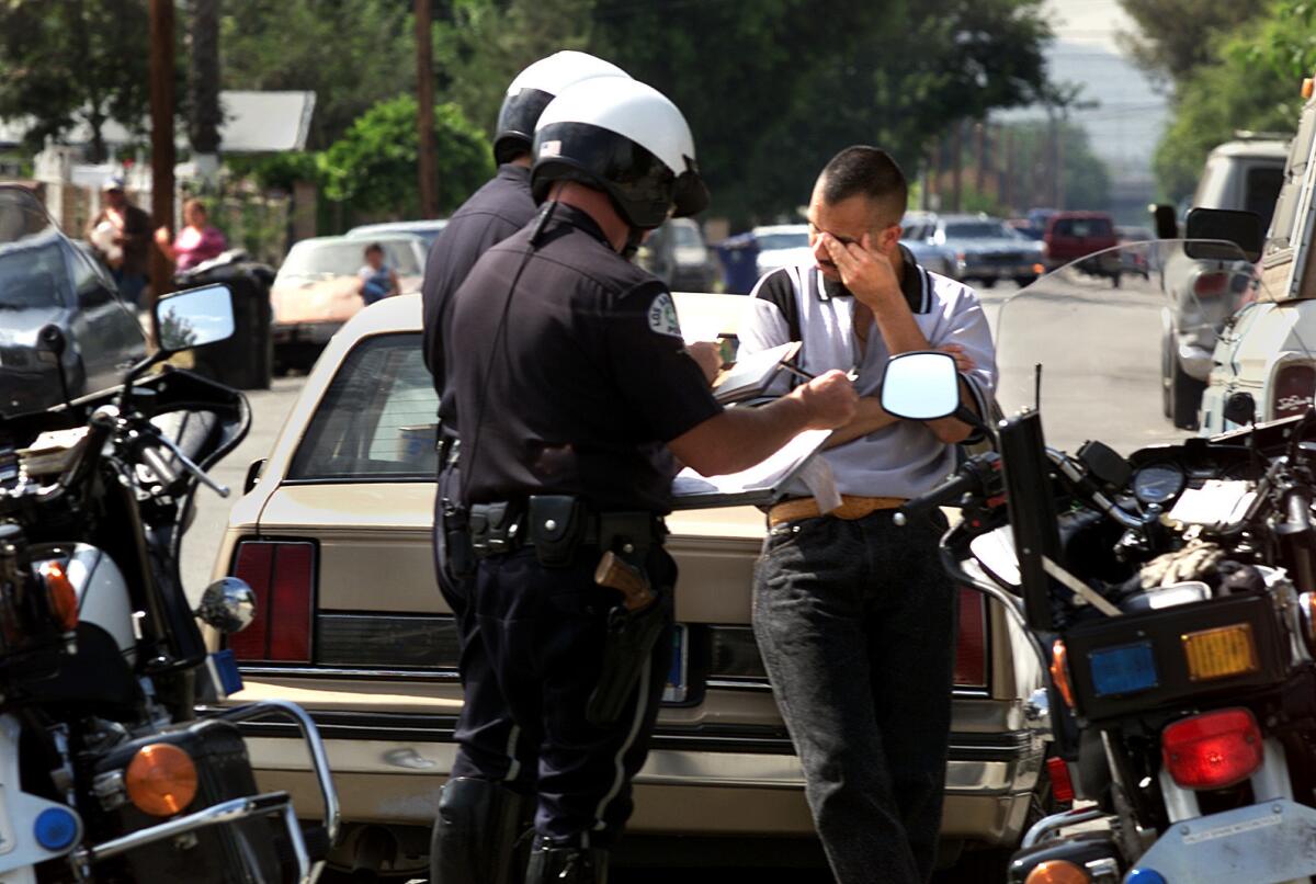 Los Angeles police officers question a driver they stopped for running a red light. They discovered he was driving without a license and impounded his car.