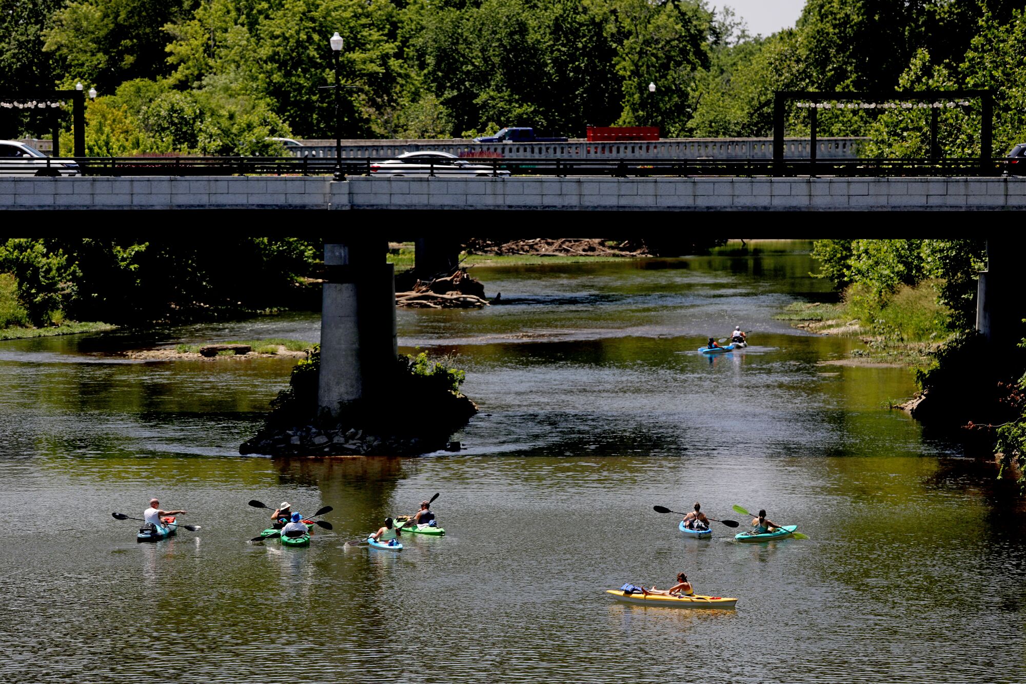 Kayakers paddle under a bridge