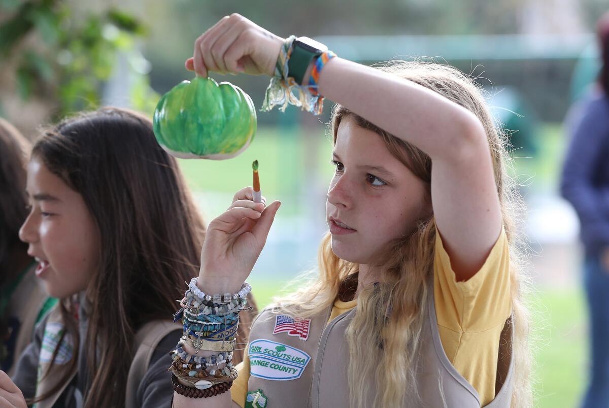 A girl decorates a pumpkin at the park