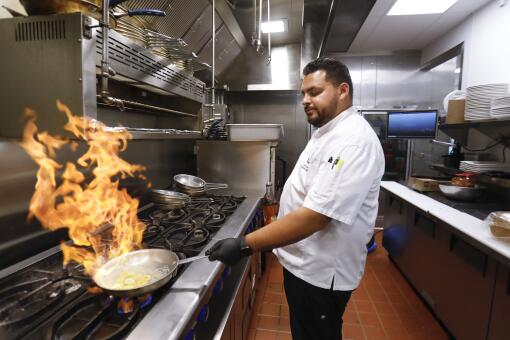 Cesar Garcia, corporate chef at Breakfast Republic, uses rum that ignites while preparing the bananas foster portion of Mr. Presley French Toast, at the restaurant's Mission Valley location, July 23, 2019, in San Diego, California.