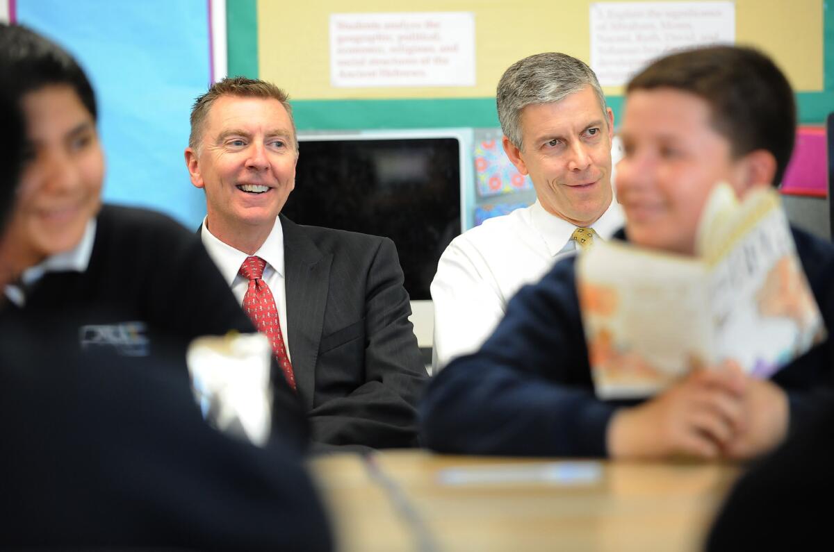 Former L.A. Unified schools Supt. John Deasy, left, and U.S. Secretary of Education Arne Duncan listen to a reading class at Dr. Julian Nava Learning Academy in Los Angeles in 2014. Duncan is stepping down from his post in December.