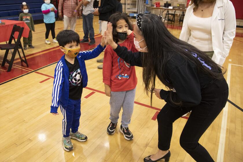 ARLETA, CA - NOVEMBER 08: Bernadette Williams high-fives her son Ocean (cq) Williams, 5, who got his COVID vaccine after his brother River, 6, at Arleta High School on Monday, Nov. 8, 2021. With the recent Centers for Disease Control and Prevention's approval of Pfizer's COVID-19 vaccine for children ages 5 to 11, Los Angeles Unified will offer voluntary vaccine access to students. The district highly encourages the vaccine for children ages 5 to 11. However, it will not be part of Los Angeles Unified's current student vaccine requirement. (Myung J. Chun / Los Angeles Times)