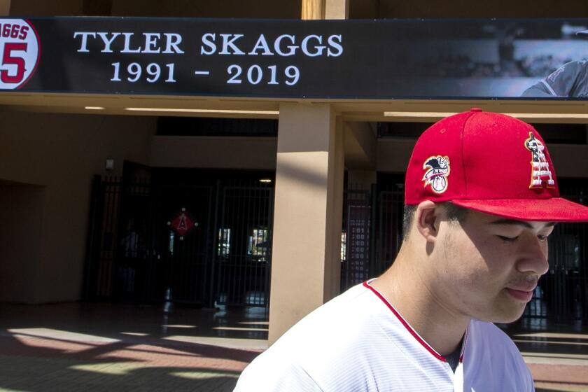 ANAHEIM, CALIF. -- MONDAY, JULY 1, 2019: Angels fan Reza Agahi, 18, of Anaheim, spends a quiet moment looking at a sign and growing memorial at Angel Stadium in Anaheim after hearing the news that Angel pitcher Tyler Skaggs was found dead in his hotel room in Texas Monday, July 1, 2019.The game was cancelled today in Texas because of his death. (Allen J. Schaben / Los Angeles Times)