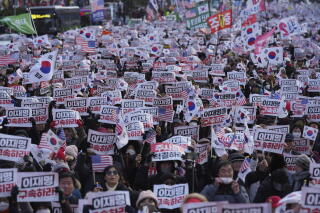 Demonstrators hold signs, some waving white flags with red and blue circles