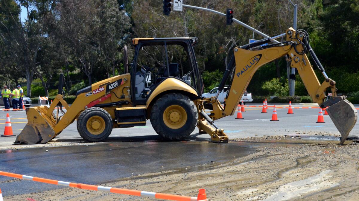 An excavator works on the opening where an Irvine Ranch Water District 20-inch water pipe broke.