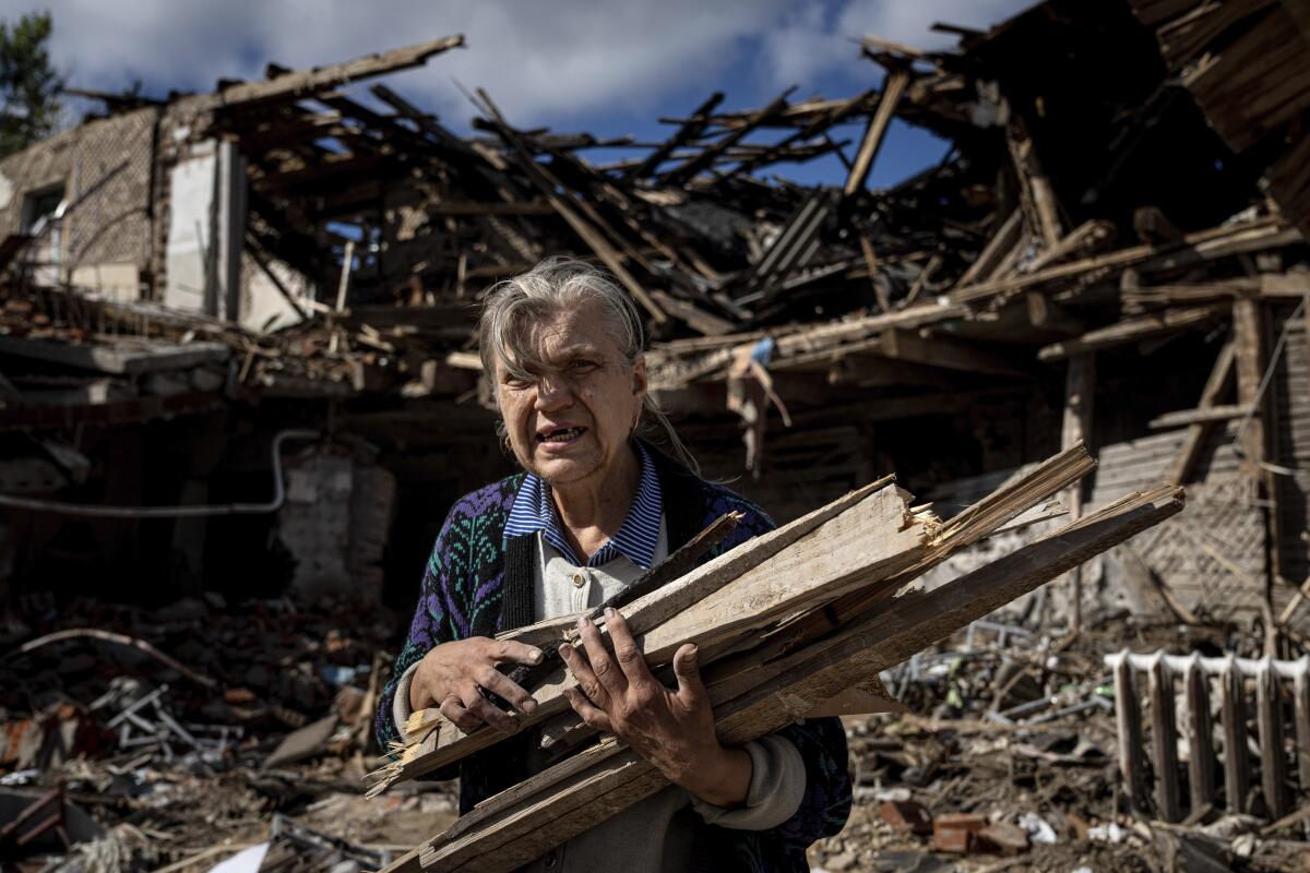 Woman collecting wood for heating from a destroyed school in Izyum, Ukraine