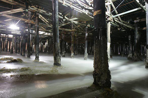 Waves roll through the pilings under the Santa Monica Pier.