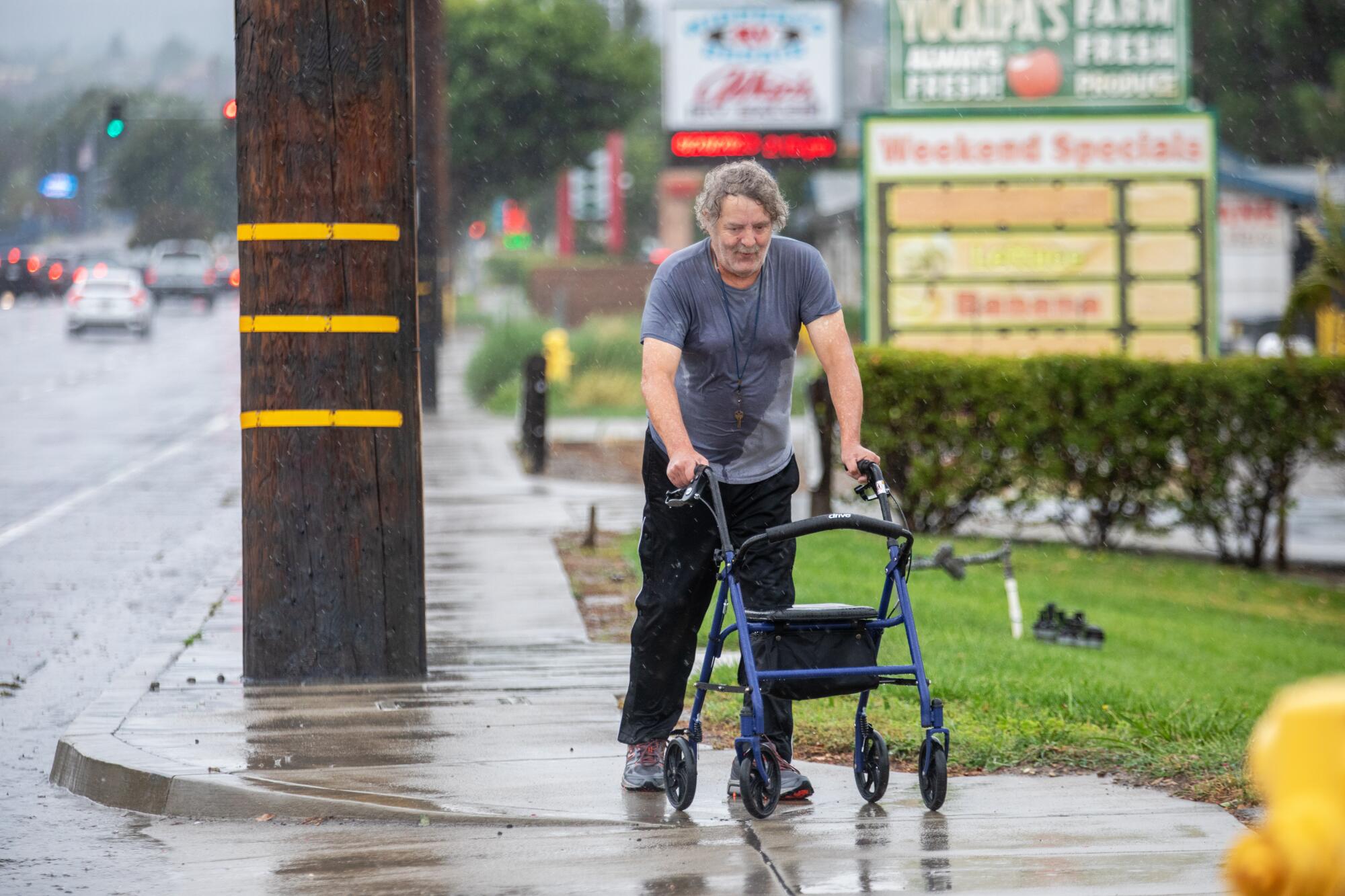 A person hold onto a walker on a wet sidewalk 