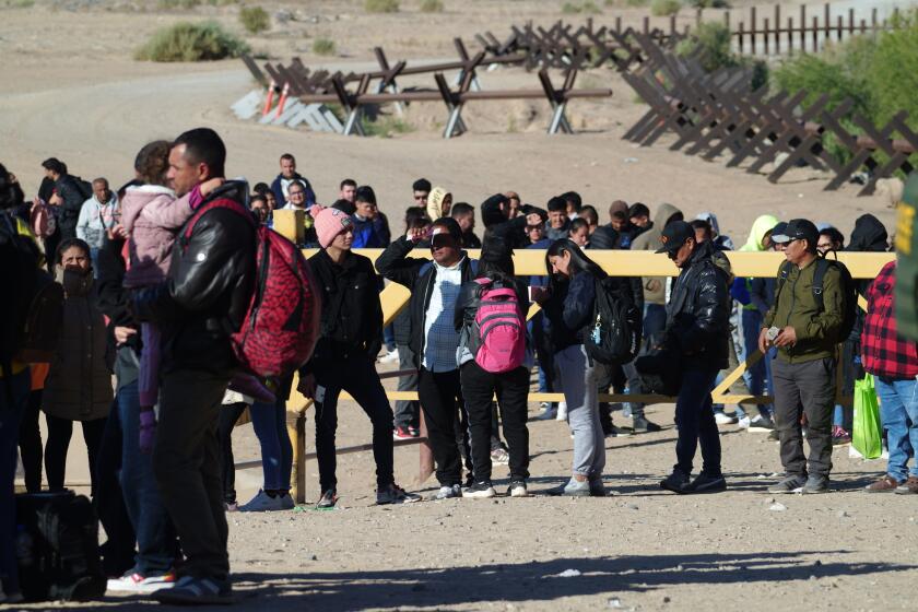 Dozens of immigrants from as far away as India and Africa wait to be processed by Customs and Border Protection officers along the border wall in Somerton, Arizona, on Friday, May 5, 2023.