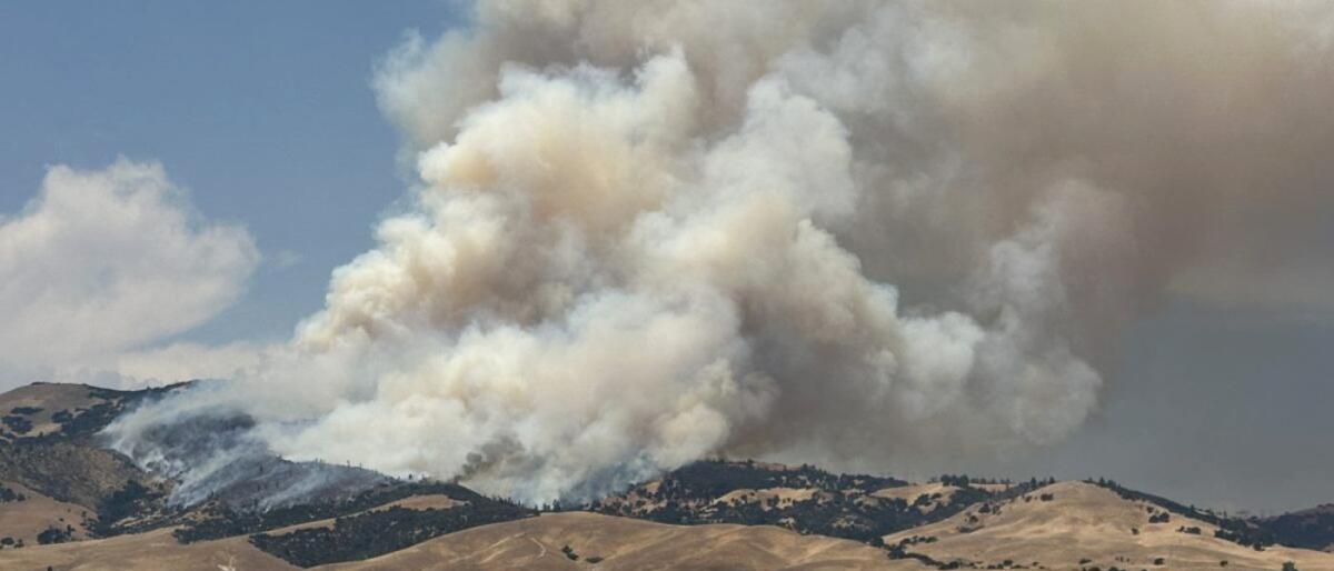 Smoke rises from Kern County hills.