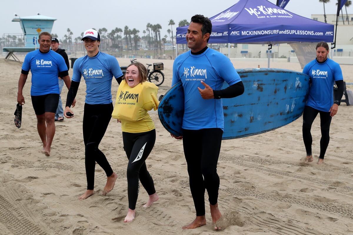 Emily Rowley walks to the ocean with instructors on Friday in Huntington Beach.