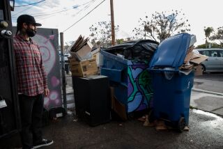 Ron Richie next to the piled up trash behind his coffee shop, GrindHouse, in Chula Vista on Wednesday, Dec. 29, 2021. Trash has been piling up at businesses and residential areas since Republic Services workers have gone on strike.