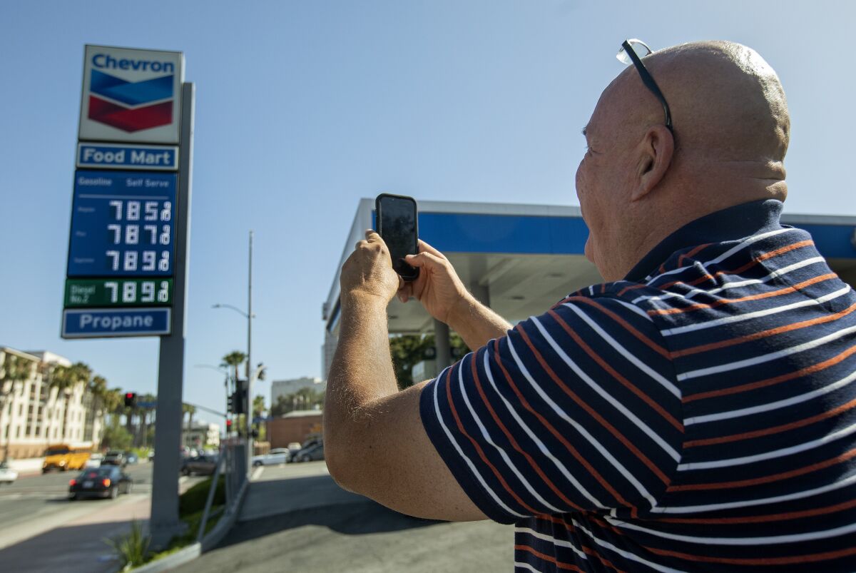 A man takes a photo of a sign showing the price of gasoline at a Chevron station in downtown L.A.