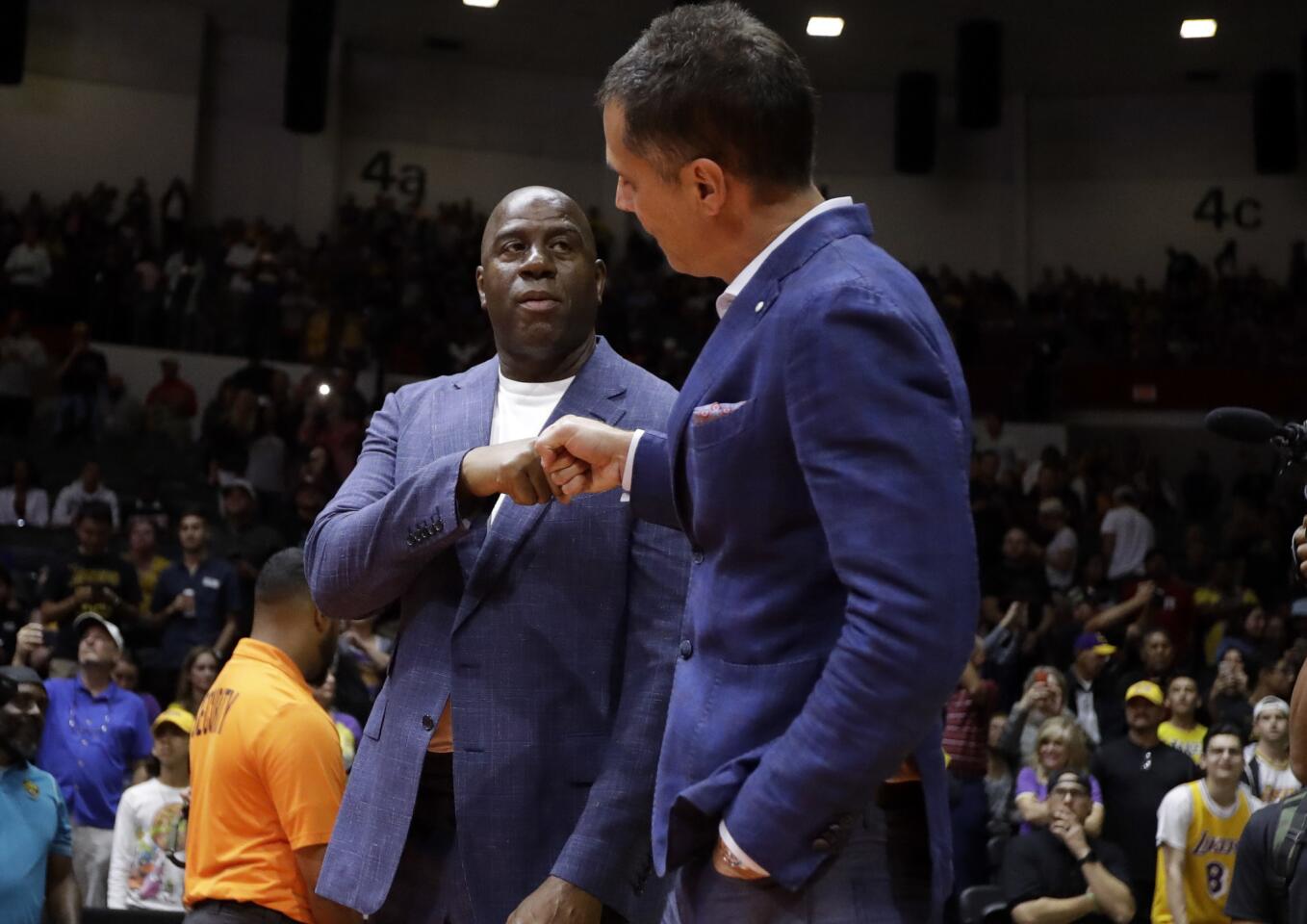 Los Angeles Lakers president of basketball operations Earvin Magic Johnson, left, bumps fists with general manager Rob Pelinka before an NBA preseason basketball game against the Denver Nuggets Sunday, Sept. 30, 2018, in San Diego.
