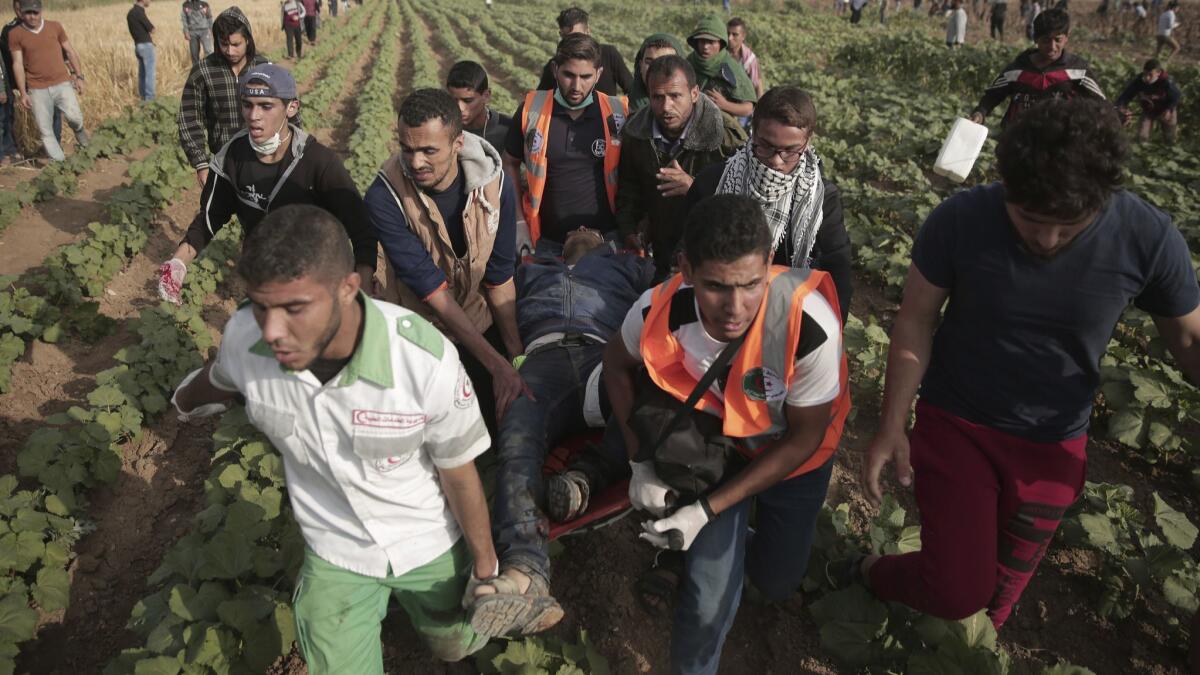 Palestinian medics carry a wounded man during a protest at the Gaza Strip's border with Israel on Friday, April 27, 2018.