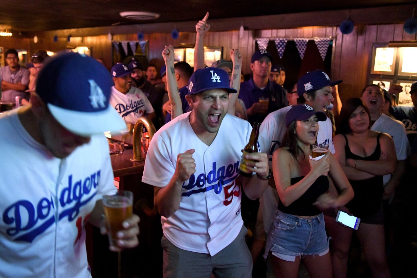 Andrew Vialpando, center, cheers with other Dodgers fans while watching the World Series at The Short Stop in Echo Park.