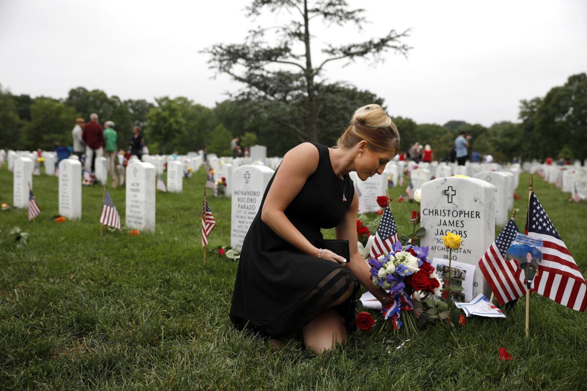 Brittany Jacobs places a flower at the headstone of her husband, Marine Sgt. Christopher Jacobs, at Arlington National Cemetery on Memorial Day in Arlington, Va. Mourners from throughout the United States travel to Arlington to visit their loved ones on Memorial Day.
