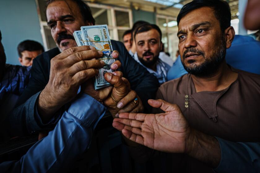 KABUL, AFGHANISTAN -- SEPTEMBER 4, 2021: Money exchangers engage in intense negotiations in the Sarai Shahzadah, Kabul's currency exchange market, where the U.S. dollar is a common trading currency, which is reopening for the first time since the Taliban took over, in Kabul, Afghanistan, Saturday, Sept. 4, 2021. (MARCUS YAM / LOS ANGELES TIMES)