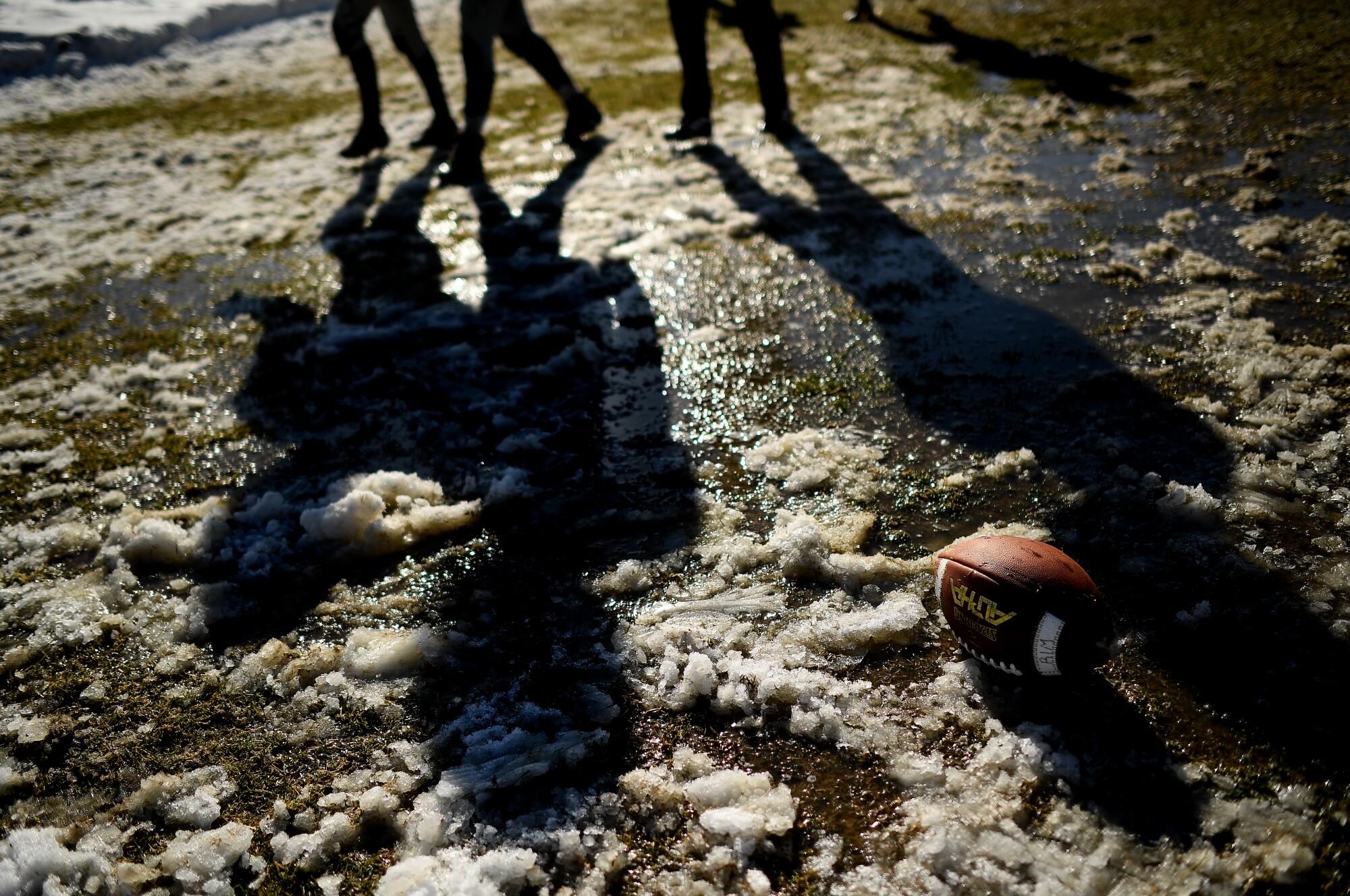 Rim of the World High School football players practice on a muddy field caused by melting snow in Rimforest on Tuesday.