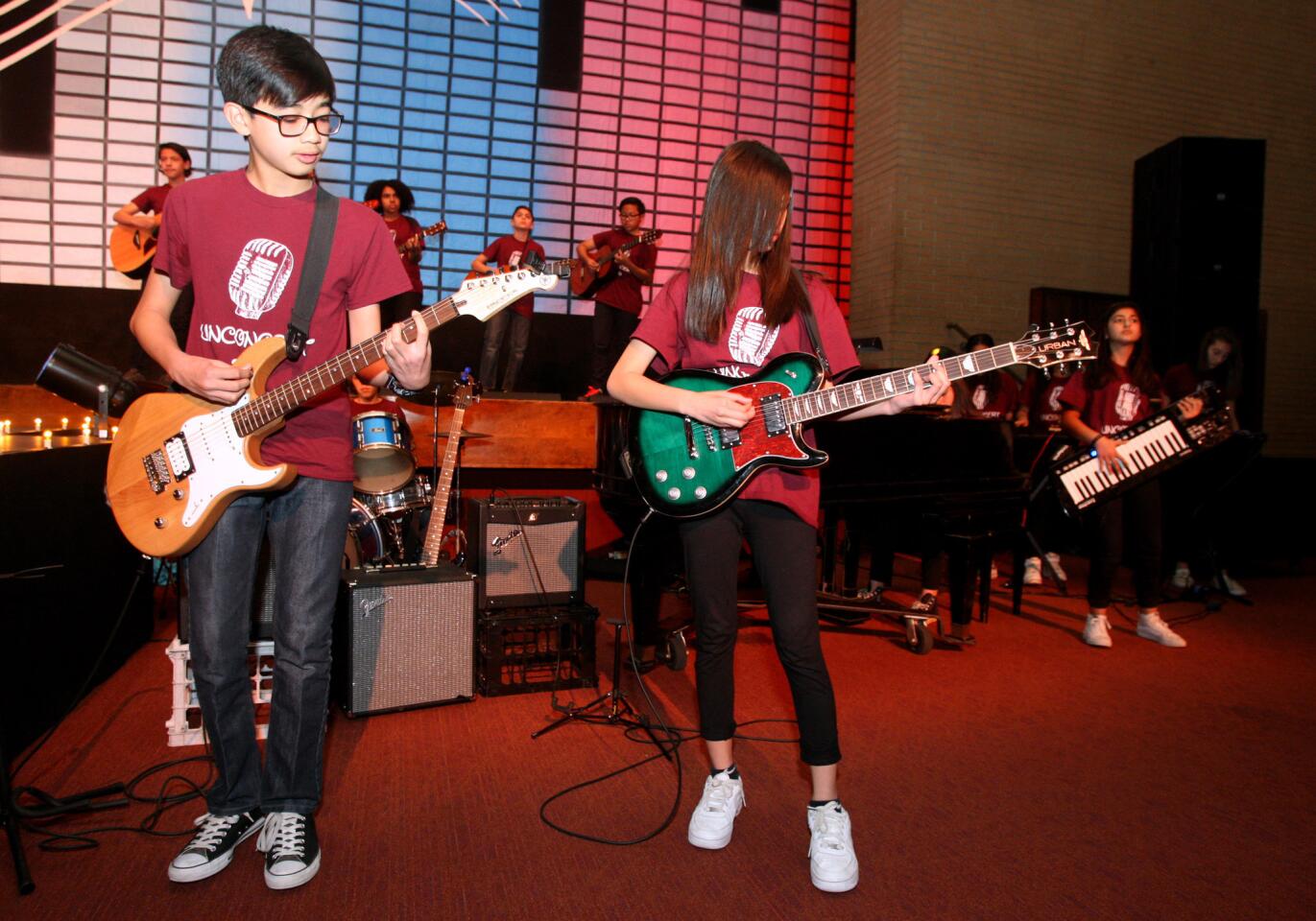 Wilson Middle School 8th grade music students Vince Hiliham, left, and Kyanna Bartolome rock away with 32 other classmates at the Unconcert '16 assembly at Glendale High School's John Wayne Performing Arts Center in Glendale on Thursday, Feb. 11, 2016. The Unconcert '16 included more than a dozen musical acts performed by Glendale High School students.
