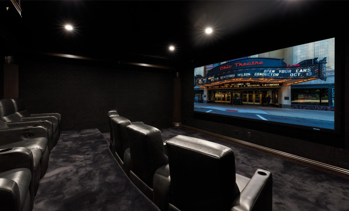 Two stacked rows of reclining seats face a large screen.