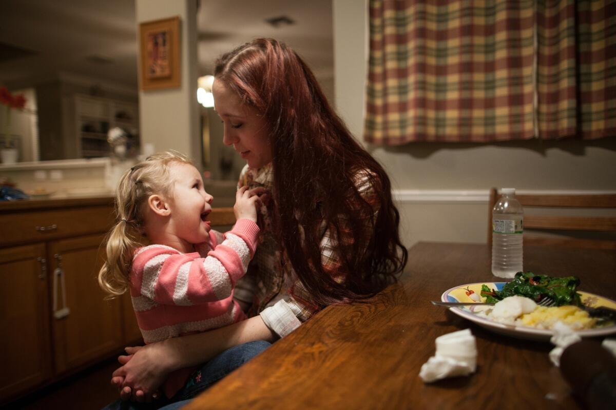 Maggie Barcellano sits down for dinner with her daughter, Zoe, 3, at Barcellano's father's house in Austin, Texas. Barcellano, who lives with her father, enrolled in the food stamps program to help save for paramedic training while she works as a home health aide and raises her daughter.