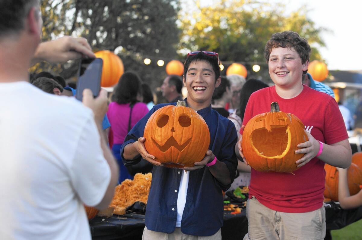 Rhys Sullivan, 14, and Japanese exchange student Homura Adachi, 15, show off their jack-o'-lanterns during a BBQ and pumpkin carving event by the Rotary Club of Newport-Balboa on Friday at Private Road Park in Newport Beach.