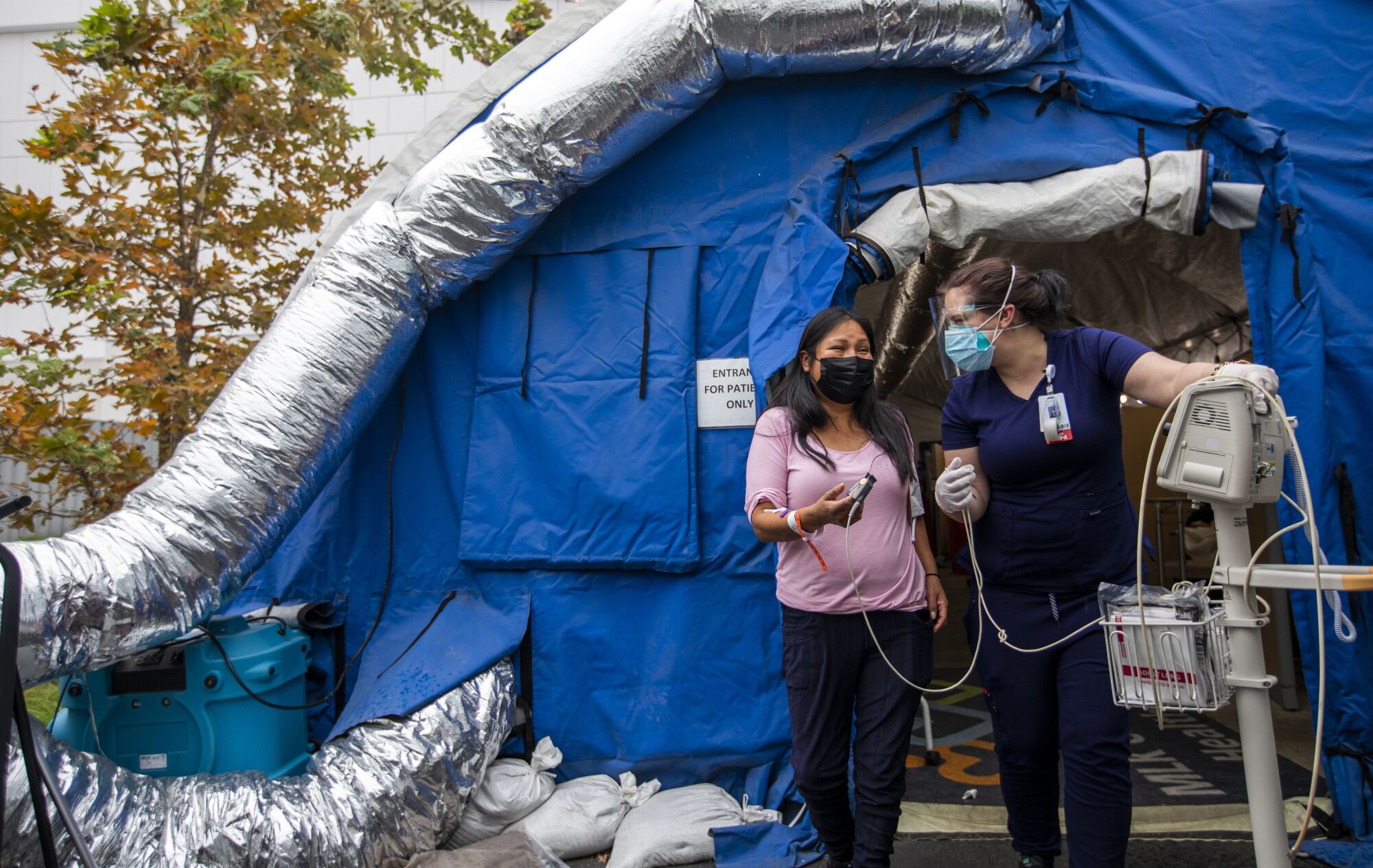 A nurse tests a patient's oxygen levels outside a triage tent