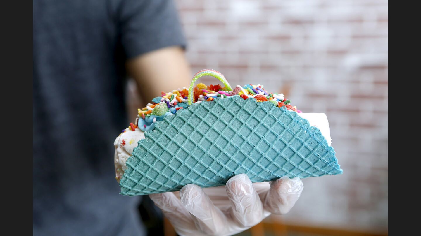 Sweet Cup owner Kenny Tran displays an ice cream taco with vanilla ice cream base, fruity pebbles and other sweet ingredients.