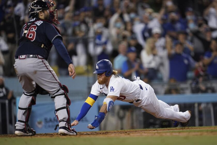 Los Angeles Dodgers' Justin Turner, right, scores past Atlanta Braves catcher Travis d'Arnaud on a single by AJ Pollock during the eighth inning of a baseball game Wednesday, Sept. 1, 2021, in Los Angeles. (AP Photo/Marcio Jose Sanchez)