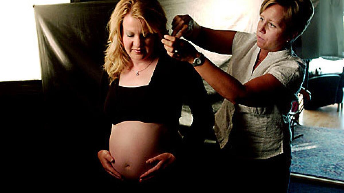 Gina Harris, left, gets a final touch-up by Helen Noakes during a session at Expressions Photography in Littleton, Colo. Harris and her husband, Rob, learned during her pregnancy that their son, David, had a fatal kidney disorder. They arranged to have maternity and infant bereavement portraits taken through the organization Now I Lay Me Down to Sleep.