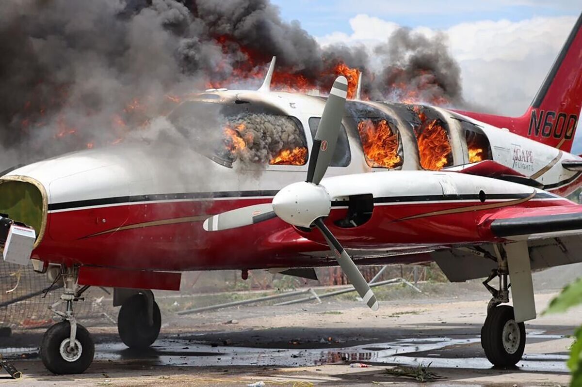 A plane burns after being set on fire by demonstrators protesting increasing violence at the Antoine Simon Des Cayes airport in Les Cayes, Haiti, Tuesday, March 29, 2022. The protest coincides with the 35th anniversary of Haiti's 1987 Constitution and follows other protests and strikes in recent weeks in the middle of a spike in gang-related kidnappings. (AP Photo/John Cadafy Noel)