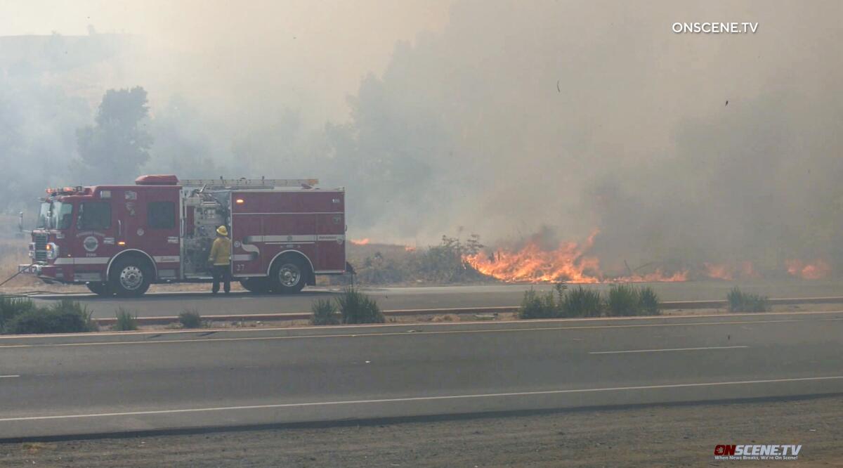 Fire truck parked on road amid flames and smoke